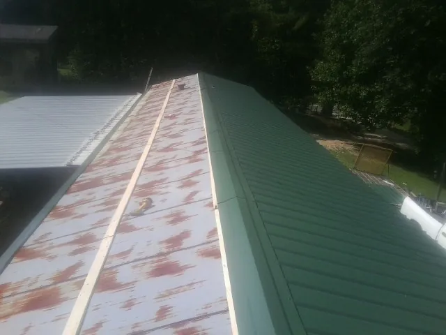 Old rusted panels beside newly installed green metal roofing — Wind Damage Roof Repair by Roofing Brothers in Thonotosassa