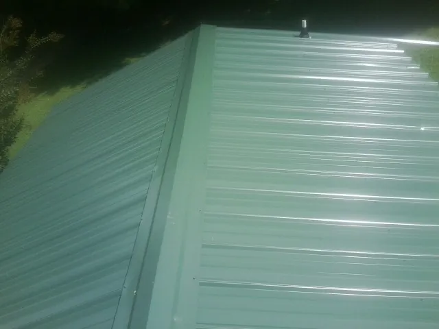 New green metal panels meeting at the ridge of a roof — Flat Roof Repair work by our crew in Thonotosassa