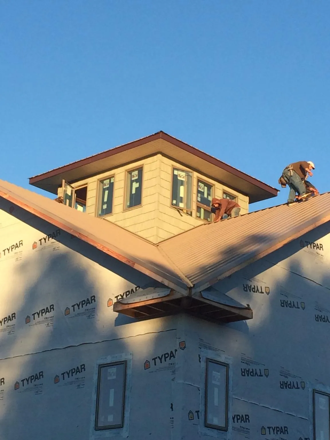 Roofers working around a rooftop cupola on a new metal roof at sunset — Roof Waterproofing in Thonotosassa by Roofing Brothers